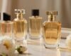 A luxurious display of premium women's perfumes, featuring the iconic Pacco Rabanne Lady Million bottle as the focal point. Set in an elegant, softly lit vanity, the perfume bottle gleams with its golden hues, accompanied by delicate floral arrangements featuring white roses and peonies in the foreground. In the middle, softly blurred, is an array of other imported fragrances, each with unique and artistic bottle designs reflecting sophistication. The background shows a warm, inviting ambiance with a hint of luxurious fabric draping, enhancing the mood of elegance. The lighting is soft and diffused, casting gentle highlights on the bottles to create an atmosphere of luxury and allure. The image captures the essence of quality and cost-effectiveness in premium perfumes.